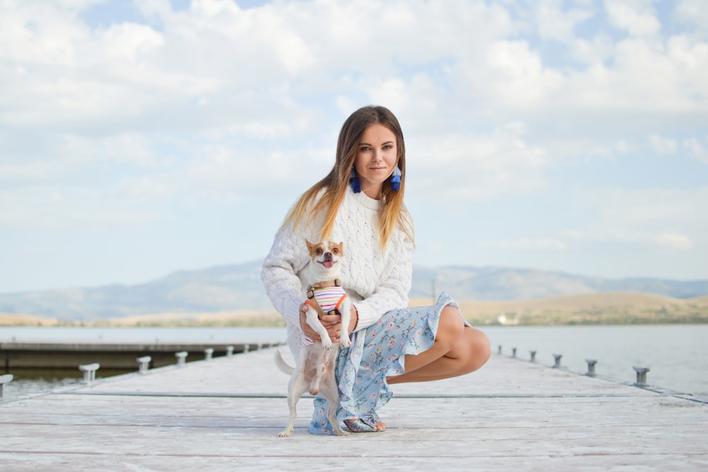 woman sitting beside dog on dock at daytime