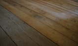 Close-up of a technician inspecting damaged hardwood flooring in a sunny South Florida home.