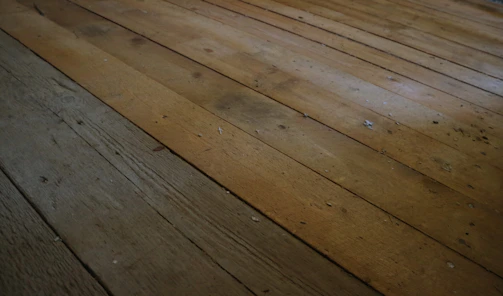 Close-up of a worker carefully restoring a worn wooden floor to its original shine.