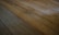 A close-up view of an aged, wooden floor with visible planks. The surface appears worn, with some dust and debris scattered across the boards.