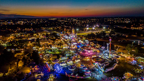 A scenic view of a theme park at sunset with lights beginning to glow.