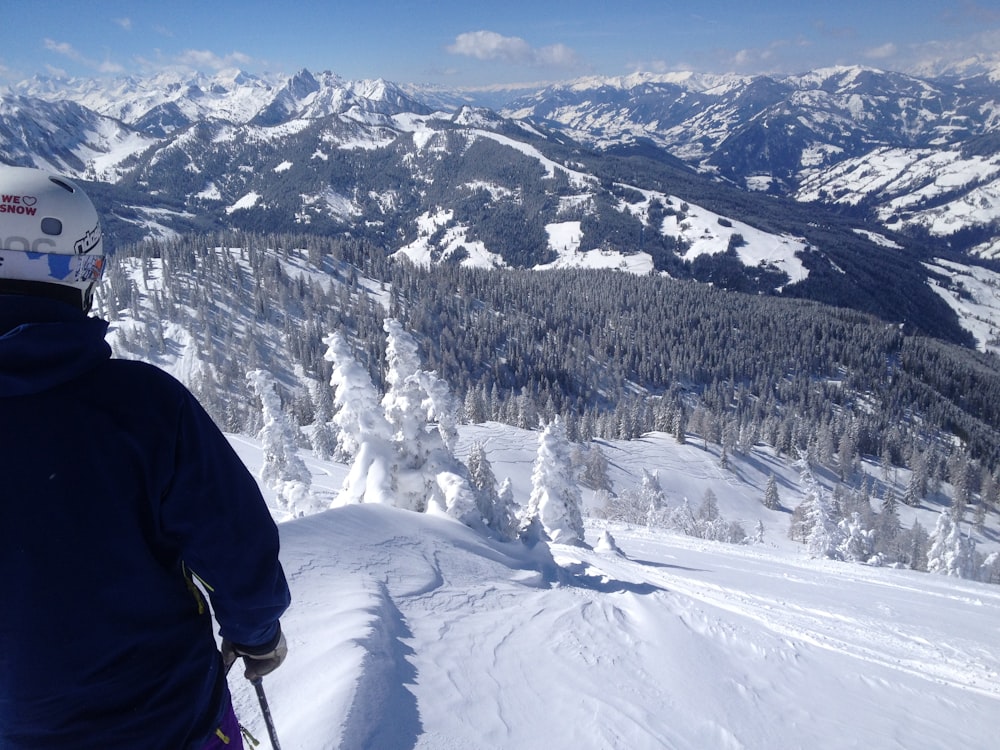 man on top of snowy mountain sightseeing cliff and forest