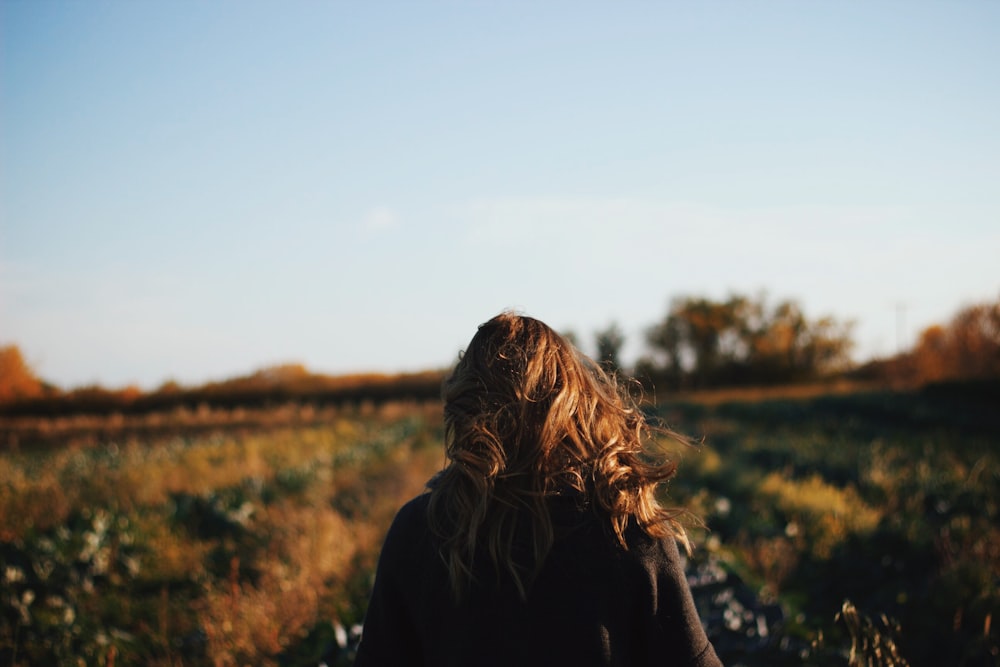 woman wearing brown jacket standing on grass field during daytime