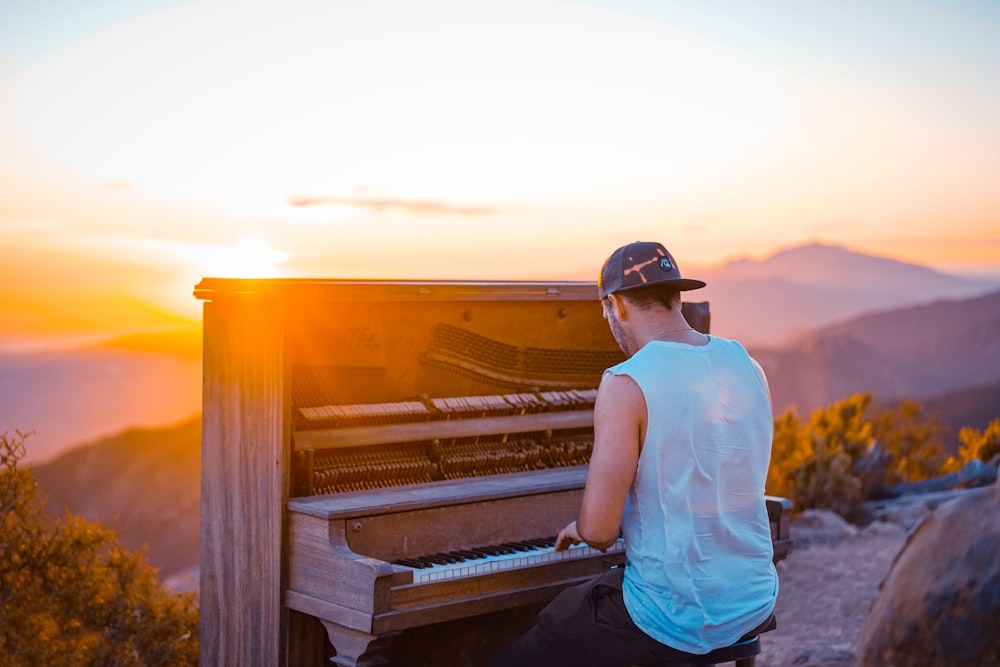 homem tocando piano ao ar livre durante o pôr do sol
