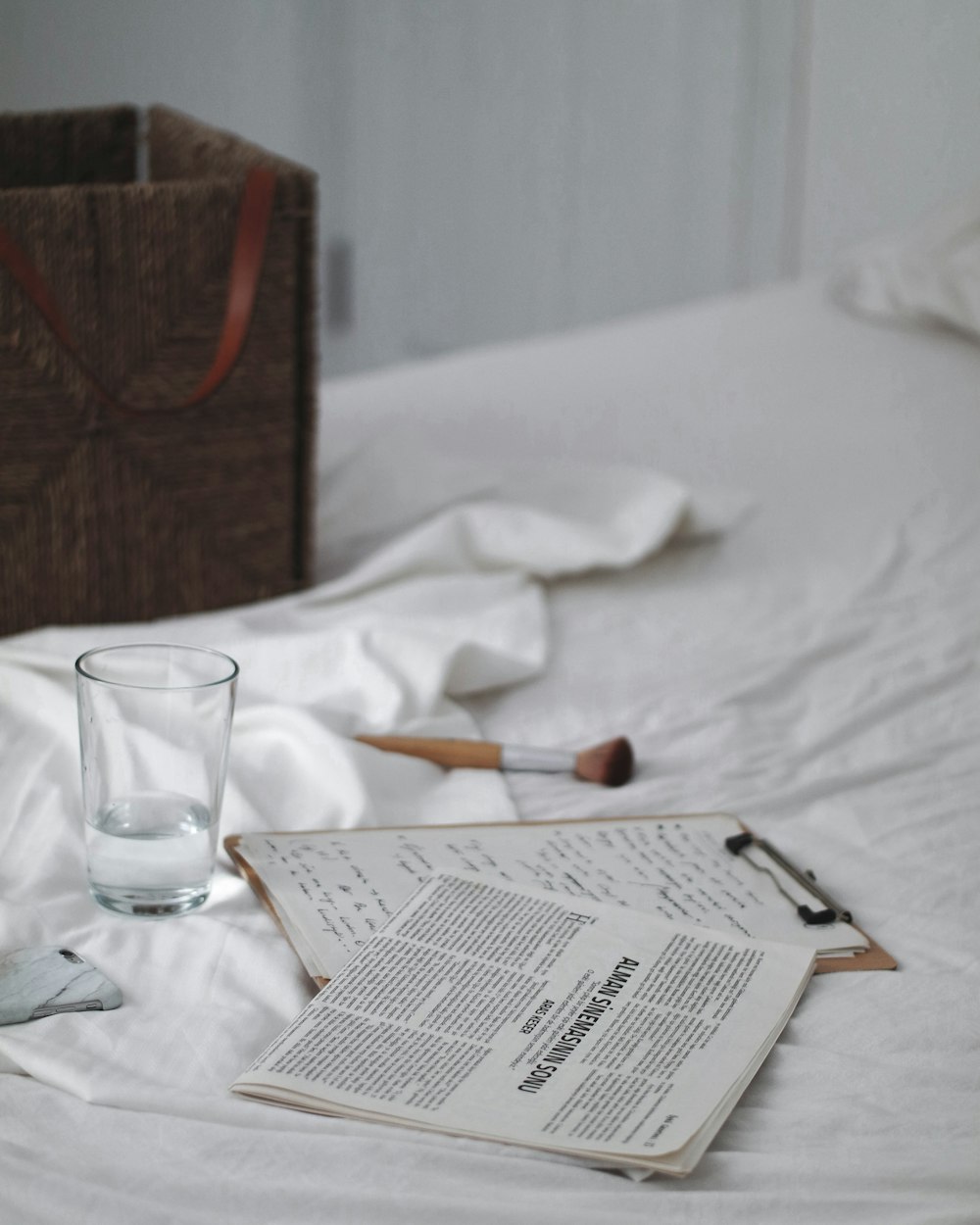 drinking glass beside clipboard on bed