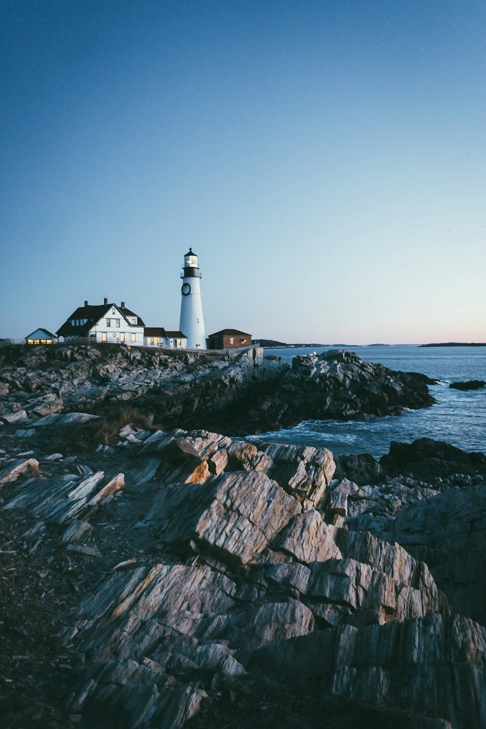 lighthouse beside body of water under blue sky