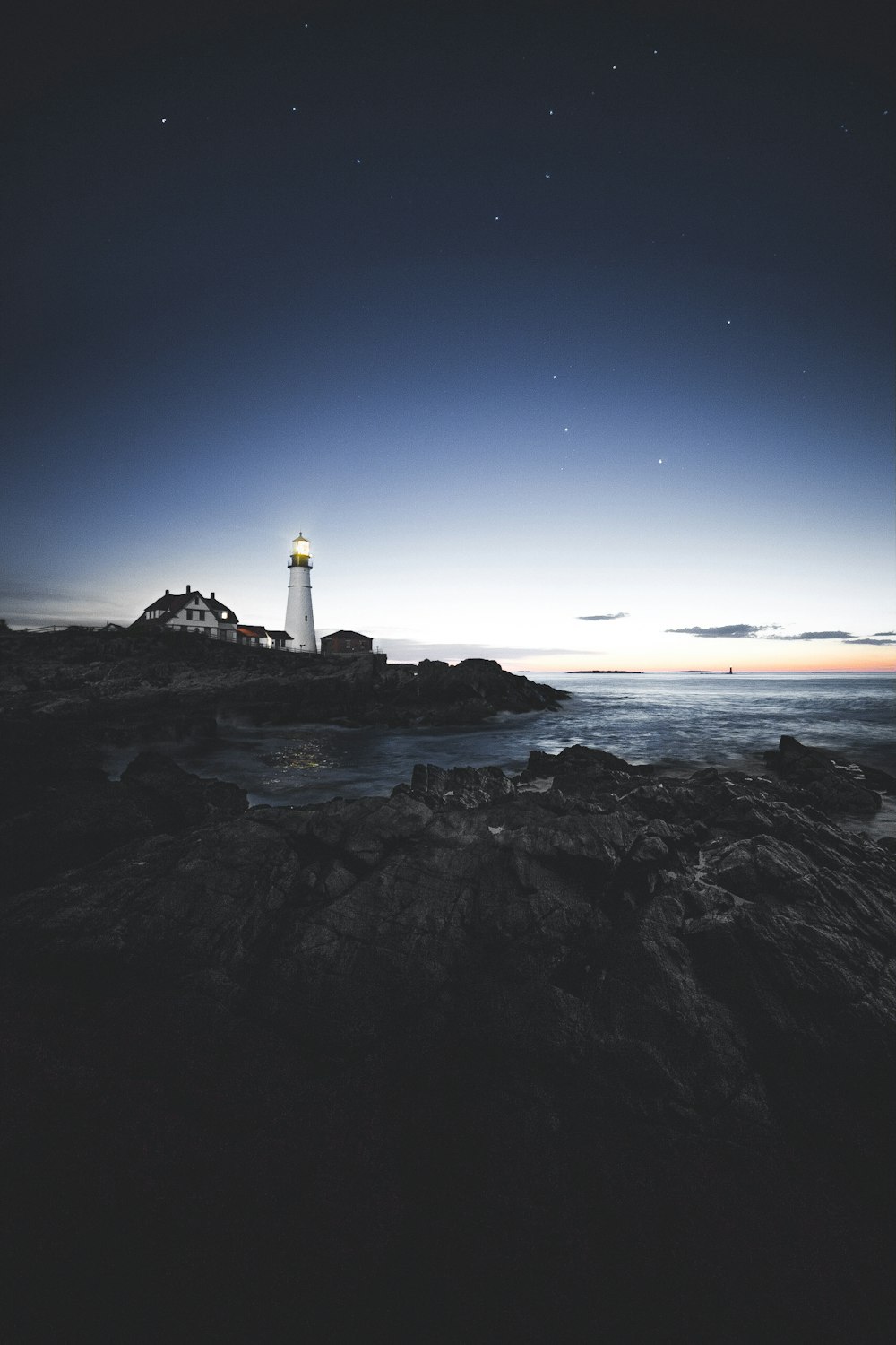 Faro al lado de la casa cerca del borde de la Isla de Piedra durante el día