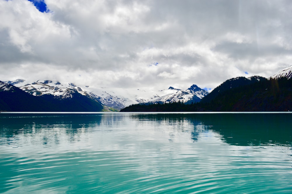 body of water near snow mountains