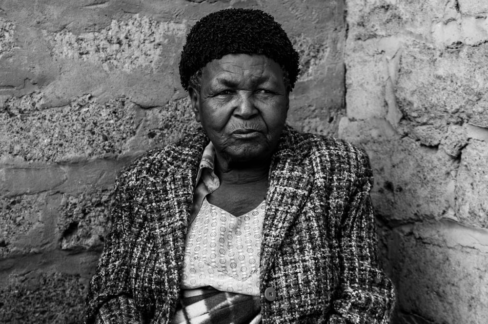 grayscale photo of woman leaning on wall