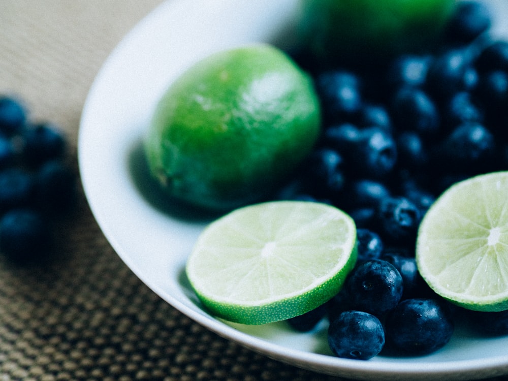 closeup photo of lime and berries on saucer