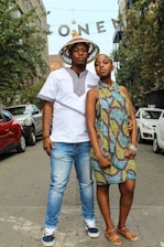 A cheerful man and woman walking confidently down a city street wearing fashionable clothes and sunglasses.