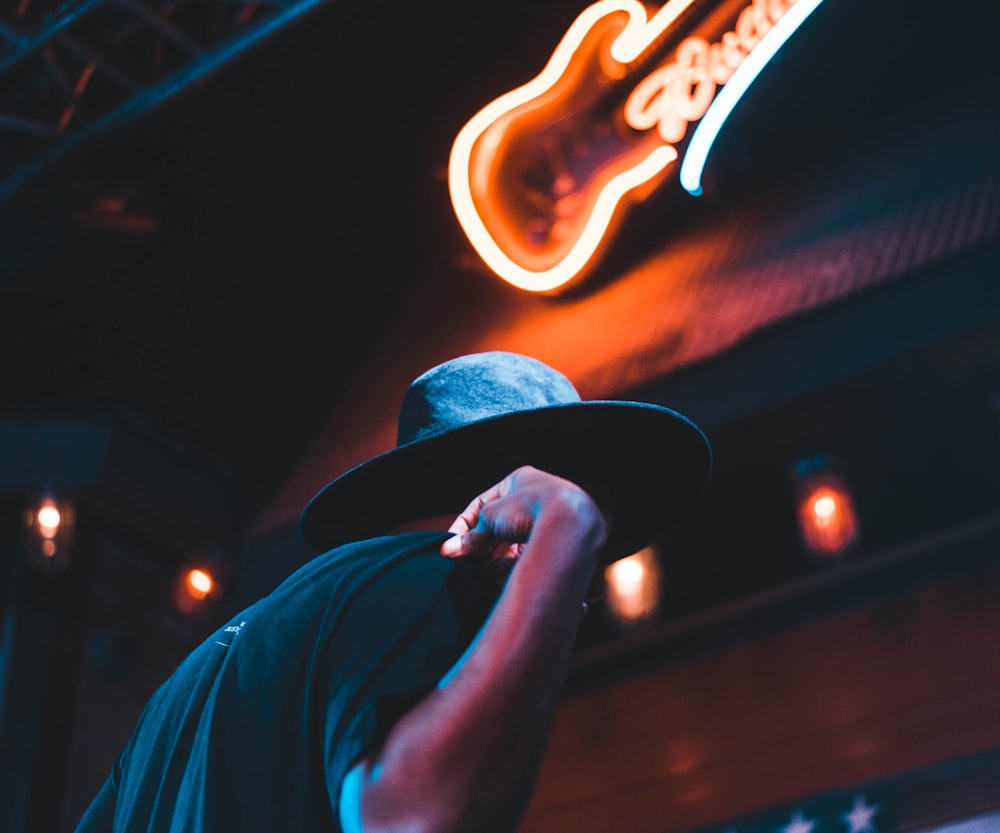 man standing under Budweiser signage at nighttime