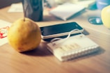 Close-up of a conference table where guests are charging phones on a sleek PromesaEvents table device showing the event schedule.