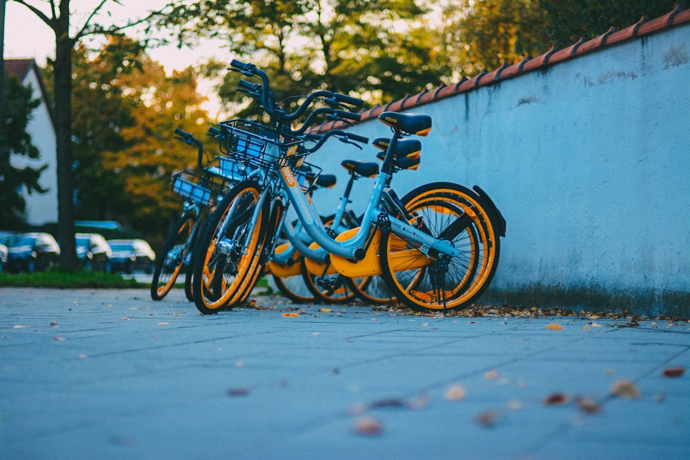 blue and orange city bicycles parked near blue wall