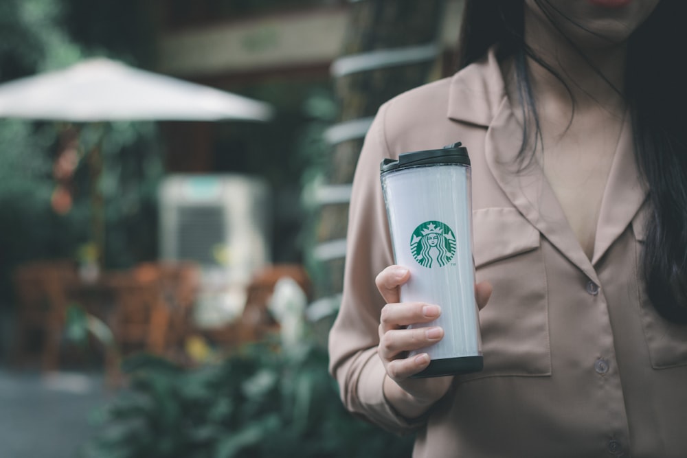 selective focus photo of woman holding Starbucks tumbler