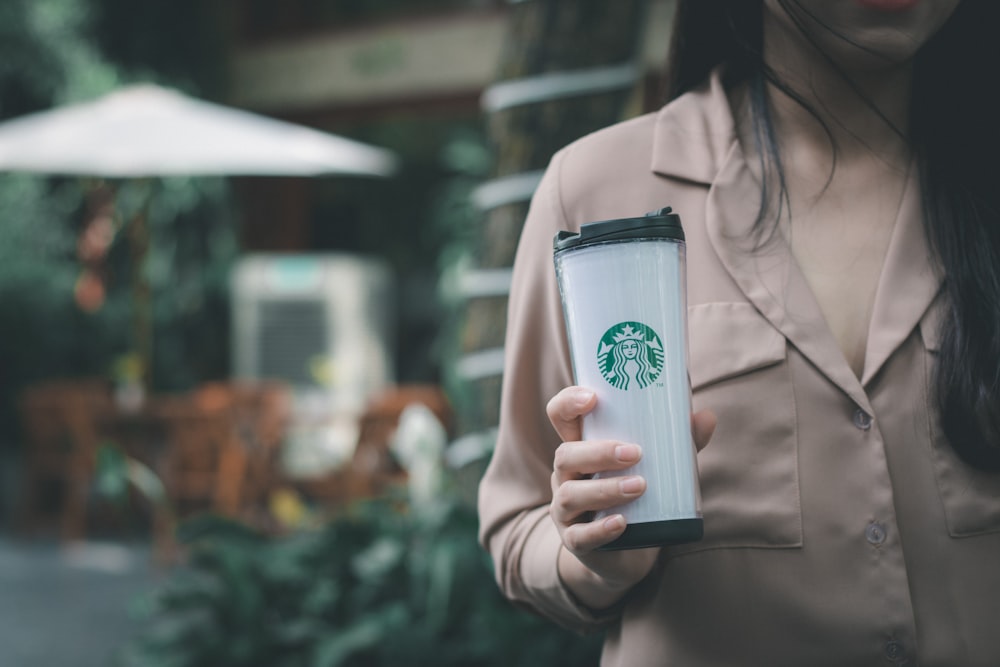 foto de foco seletivo da mulher segurando o tumbler Starbucks