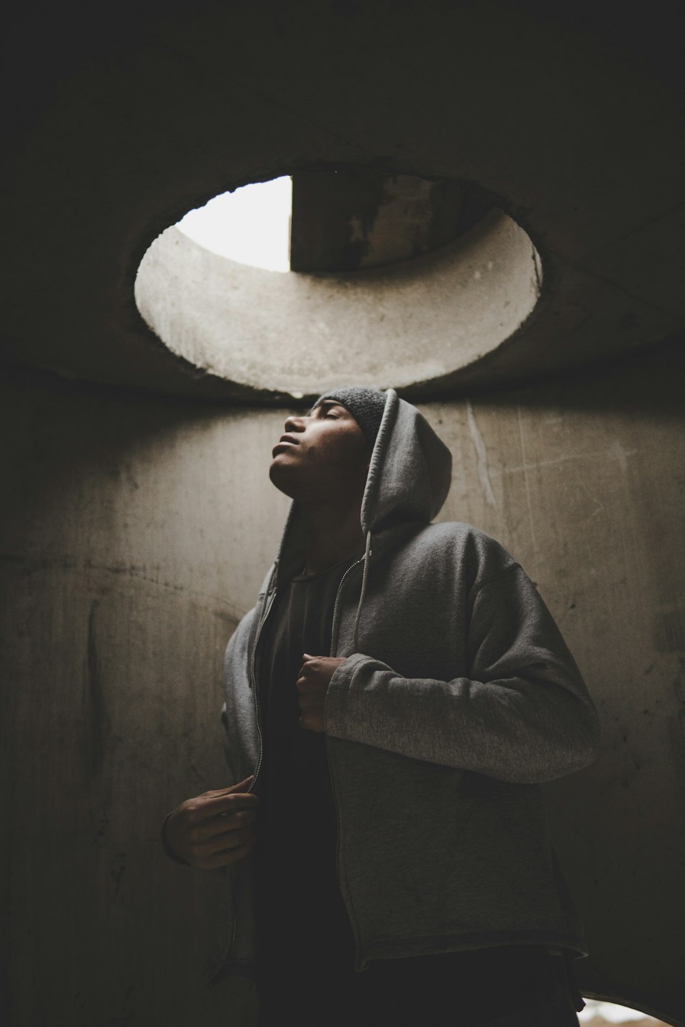 man wearing hoodie standing under manhole