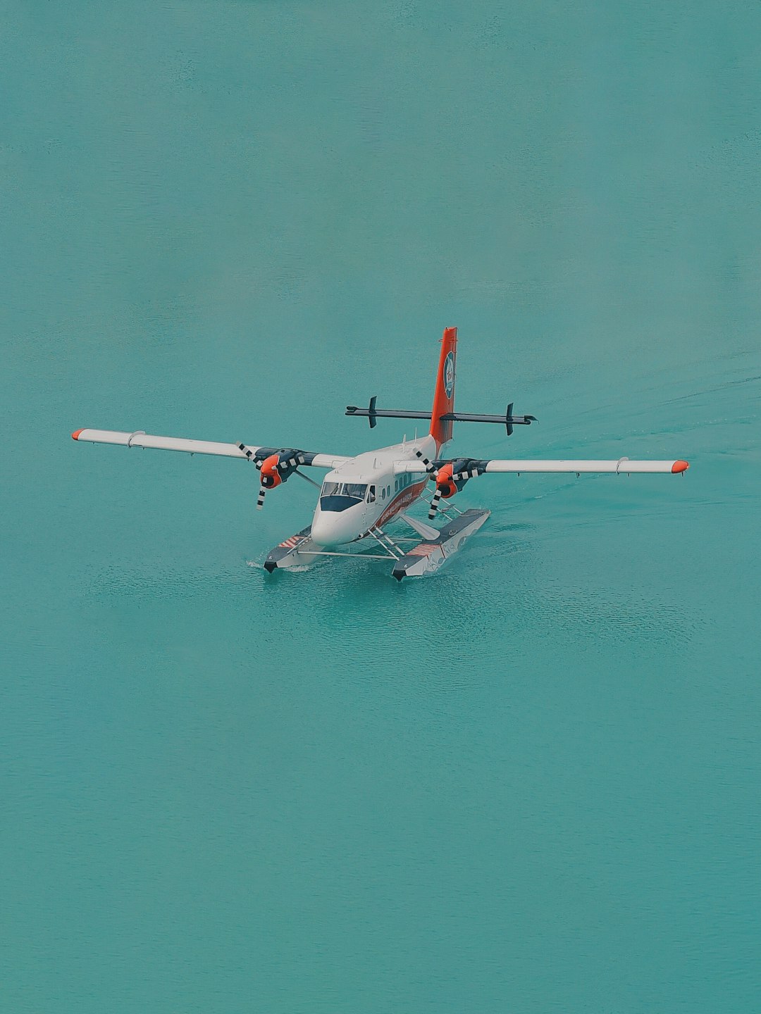 white and orange biplane landed on body of water