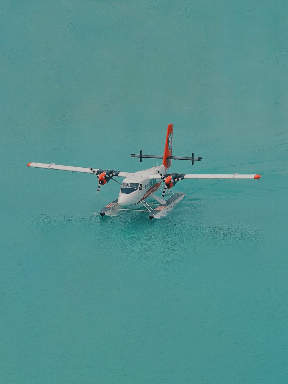 white and orange biplane landed on body of water