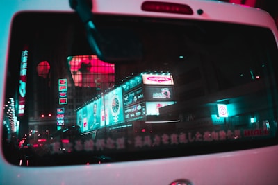 A night shot of a commuter’s car with illuminated stick2earn decals reflecting city lights in Calgary.