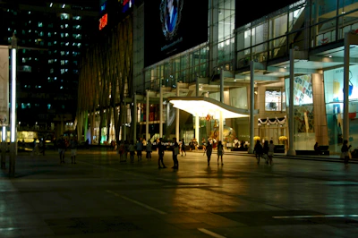 A commercial building with sleek architecture and storefronts bustling with activity.