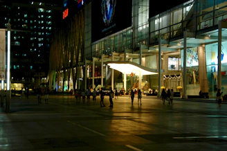 A commercial building with sleek architecture and storefronts bustling with activity.