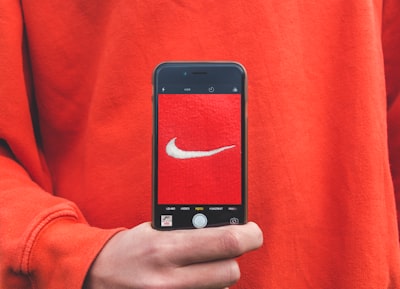 Identyfikacja wizualna – co to takiego i dlaczego jest ważna dla twojej firmy? - person holding iPhone taking picture on Nike label