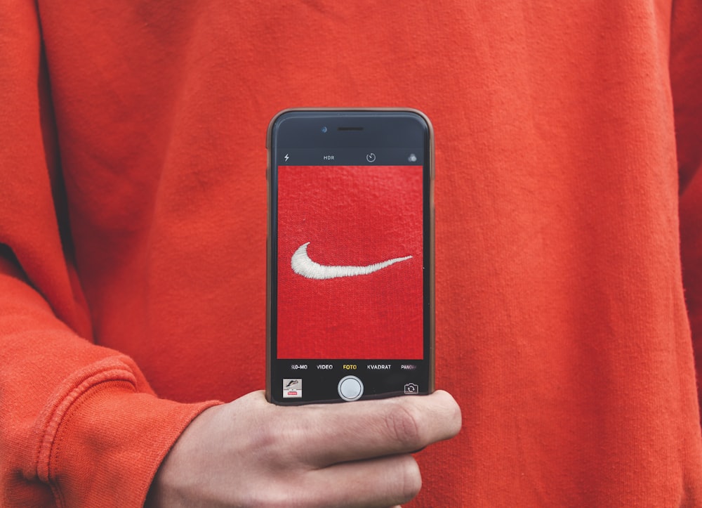 personne tenant un iPhone prenant une photo sur l'étiquette Nike