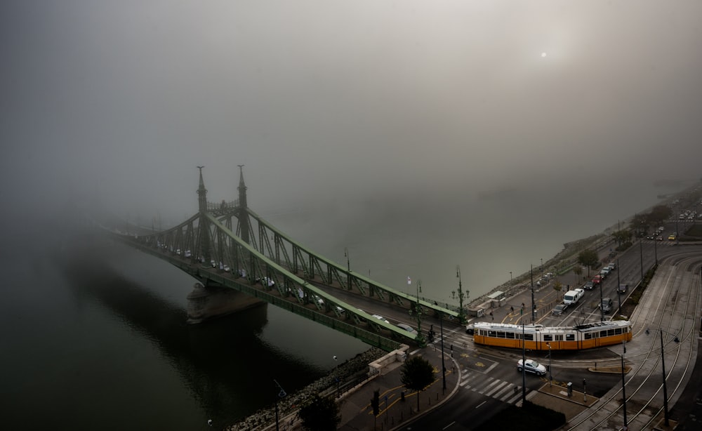 train towards gray concrete bridge covered by white clouds