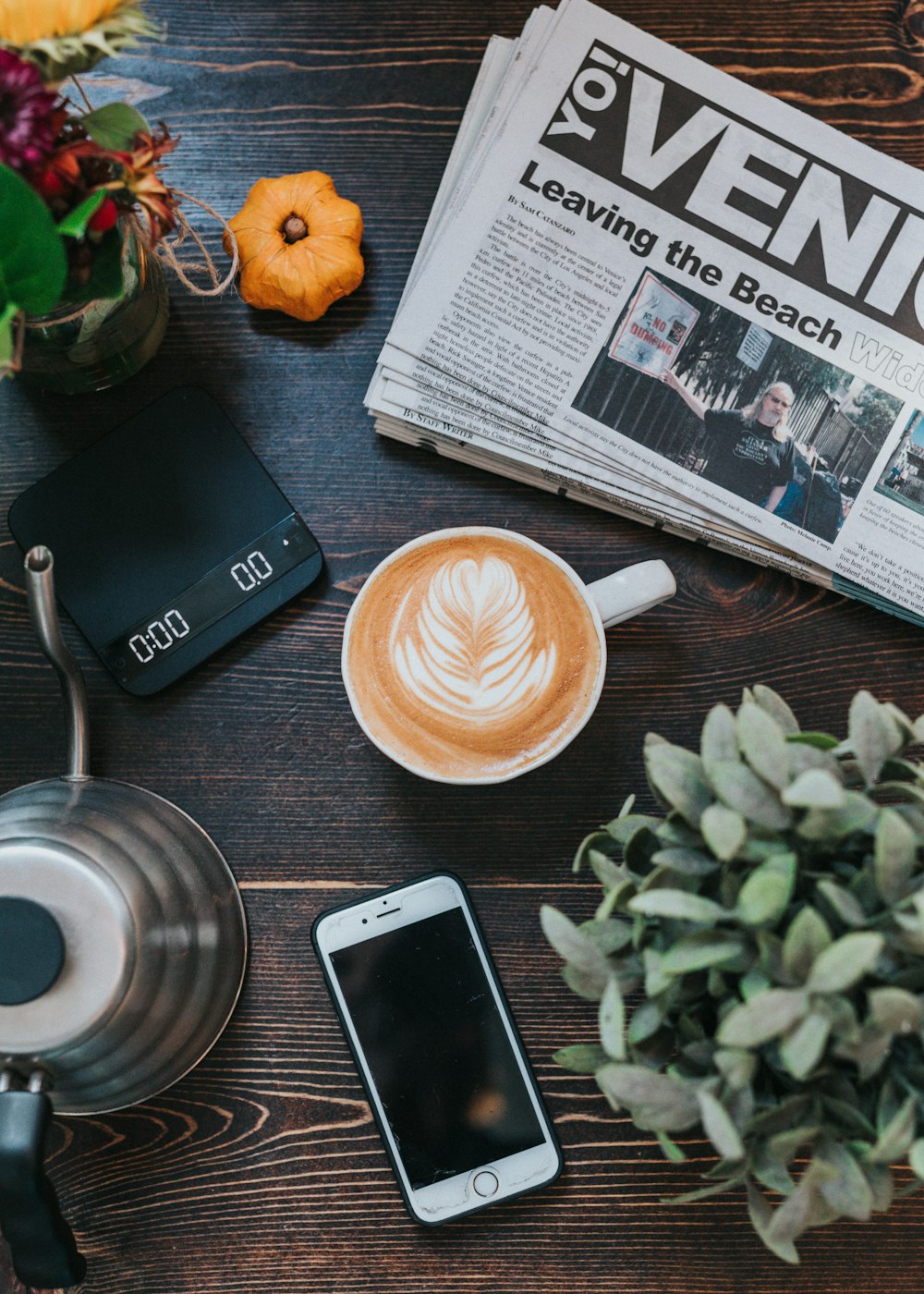 gold iPhone 6 near mug with coffee latte and teapot on table