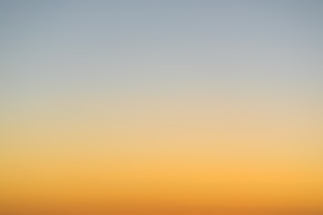 a plane flying in the sky at sunset