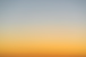 a plane flying in the sky at sunset
