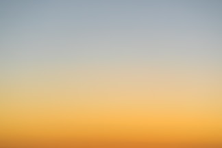 a plane flying in the sky at sunset