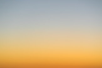 a plane flying in the sky at sunset
