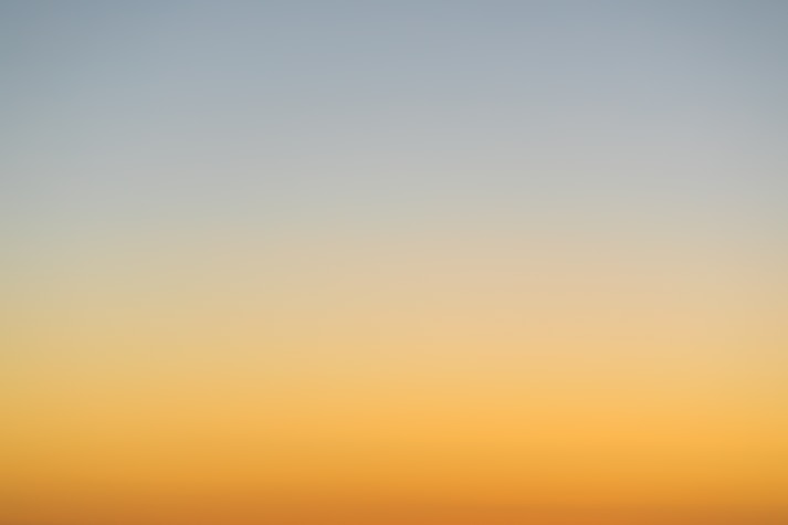 a plane flying in the sky at sunset