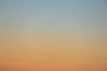 a plane flying in the sky at sunset