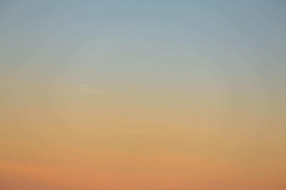 a plane flying in the sky at sunset