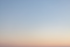 a plane flying in the sky at sunset