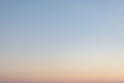 a plane flying in the sky at sunset