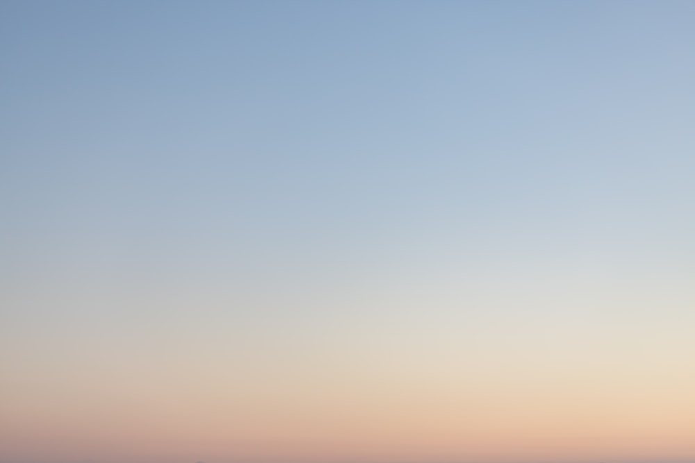 a plane flying in the sky at sunset