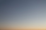 a plane flying in the sky at sunset