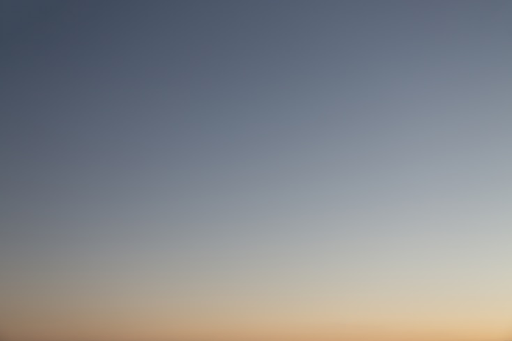 a plane flying in the sky at sunset