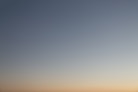 a plane flying in the sky at sunset