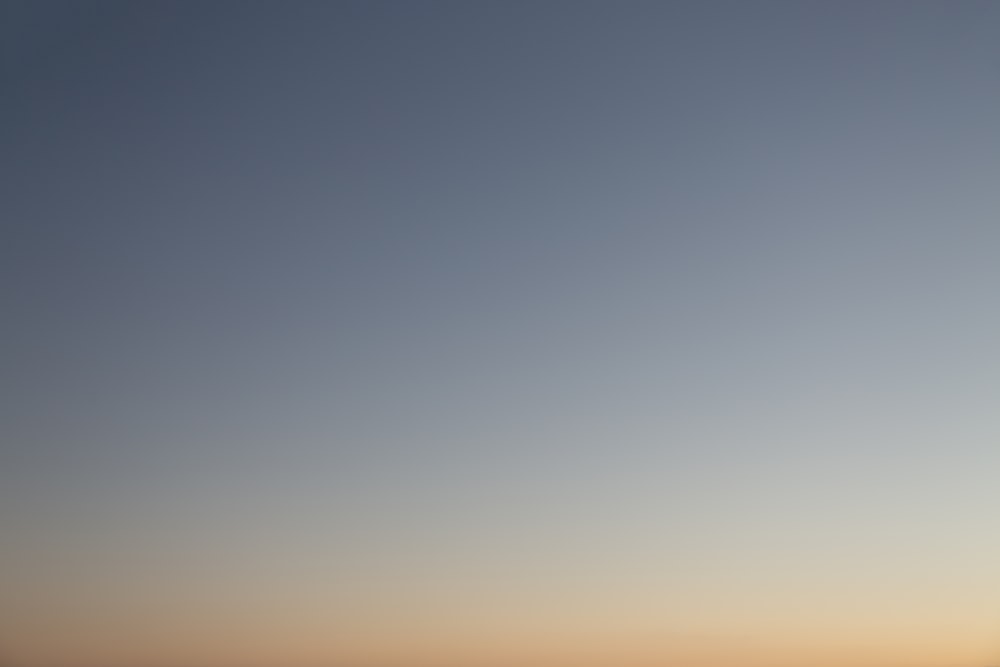 a plane flying in the sky at sunset