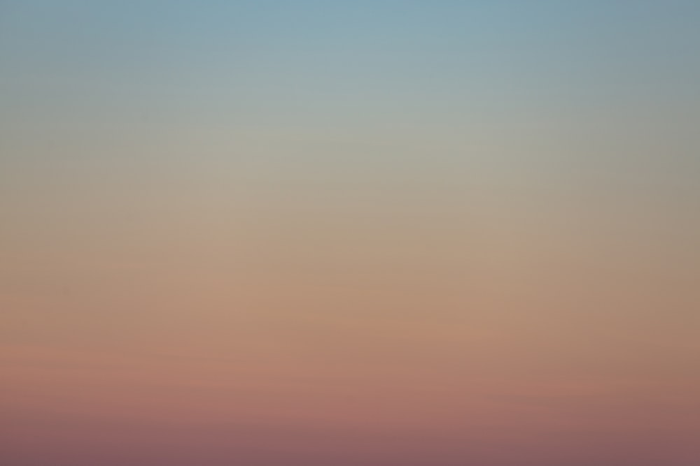 a plane flying in the sky at sunset