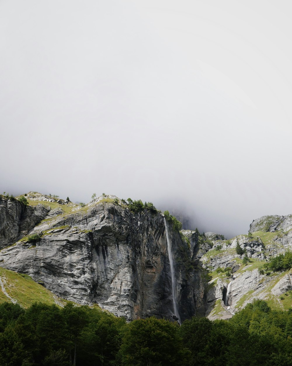 mountains covered with green trees under cloudy sky during daytime