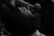 A person is lying down, facing upwards in a dimly lit environment. Their hand is resting on their forehead, and they are wearing glasses. The focus is on the calmness and introspective moment.