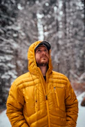 men wearing orange down jacket standing on snow field near trees