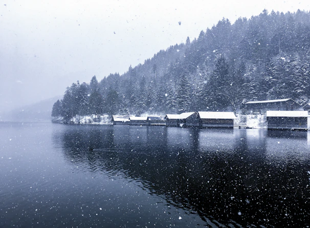 Snow gently falling on a serene lakeside cabin in the Canadian Rockies.