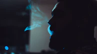 Profile shot of a fighter exhaling in slow motion, illuminated by electric blue light.